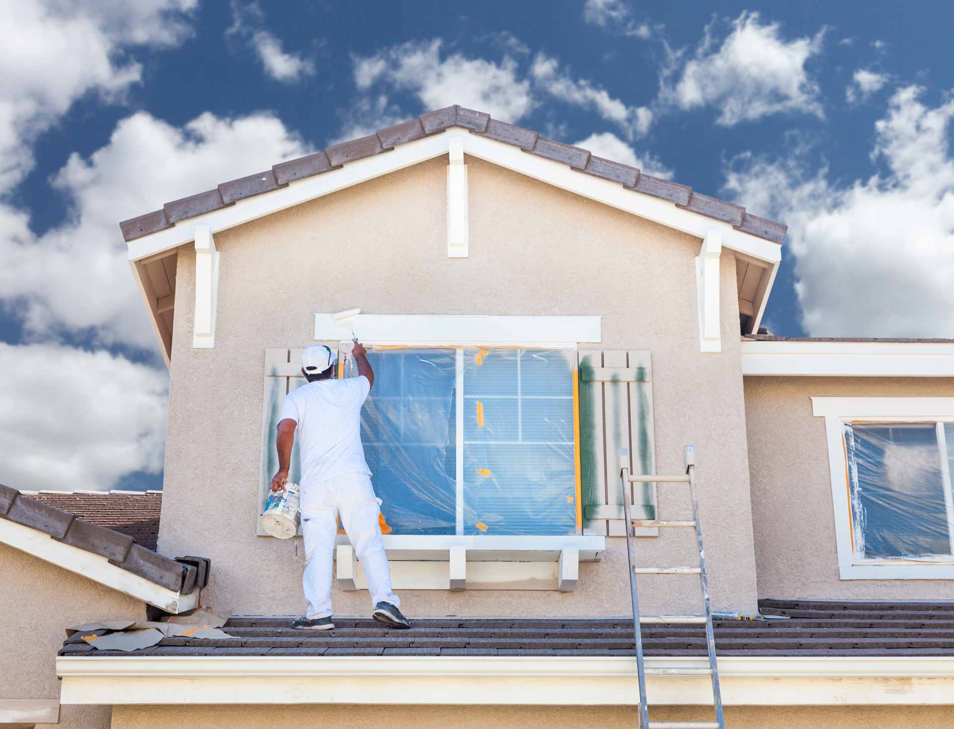 Painter working on roof of house