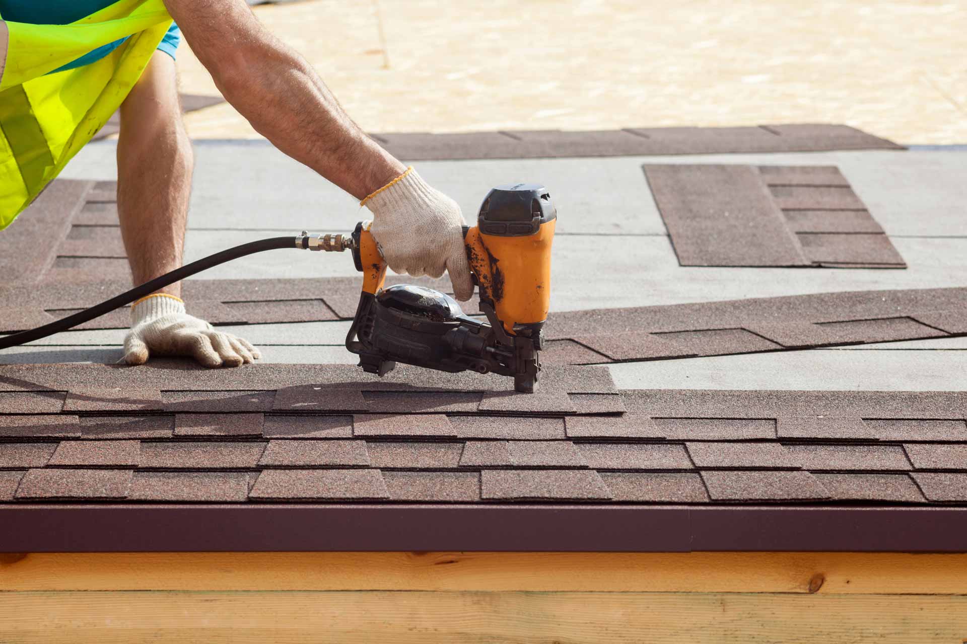A man installing shingles on a new roof